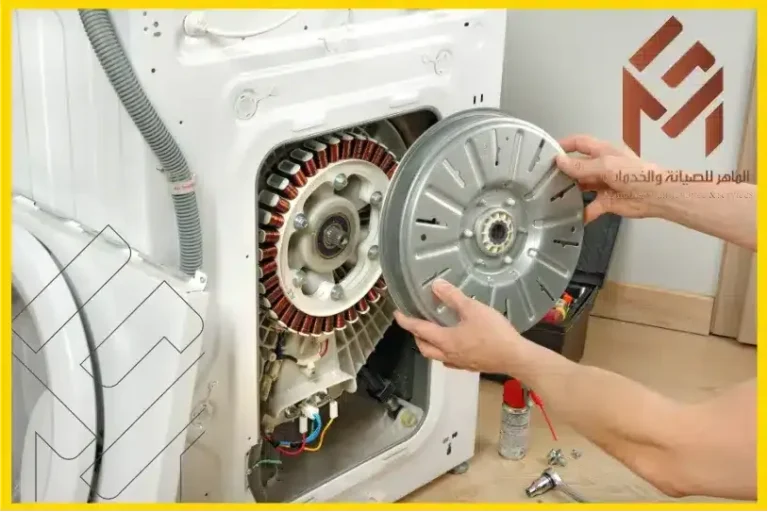 شخص يقوم بفك أو تركيب دائرة محرك غسالة أوتوماتيكية بيضاء، ويظهر جانبها الداخلي والمكونات الكهربائية. توجد أدوات على الأرض وشعار باللغة العربية في الأعلى على اليمين.مزايا وعيوب محرك الدفع المباشر في غسالة الملابس