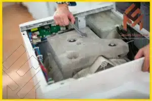 صيانة غسالات اتوماتيك مكة مفتوحة يتم إصلاحها باستخدام مفتاح ربط.