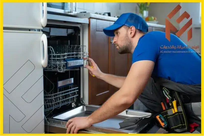 فني يلبس تيشيرت ازرق ينظر الى داخل غسالة الصحون