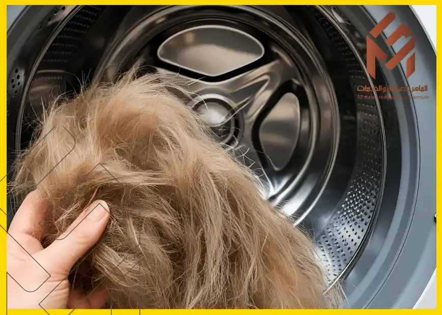 يد تمسك بكتلة من الفرو الأشقر أمام غسالة مفتوحة من الداخل.كيفية إزالة شعر الكلاب والقطط من الملابس والأثاث النسيجي