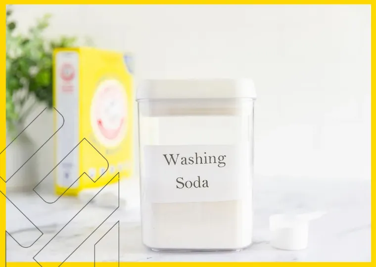 علبة تحتوي على صودا للغسيل موضوعة على سطح، مع عبوة صفراء غير واضحة في الخلفية. استخدام صابون الأطباق العادي