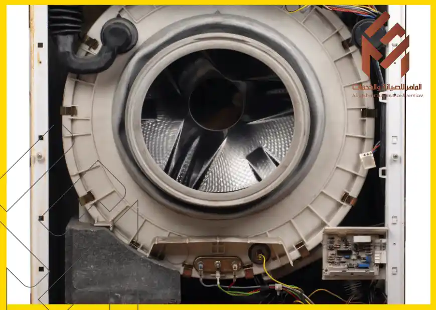 صورة لجزء داخلي من غسالة تعرض المكونات التقنية والمعدات، مع التركيز على الأسطوانة والمحرك، ضمن موضوع صيانة الغسالات في مكة المكرمة. توجد شعار الشركة في الزاوية العلوية اليمنى.