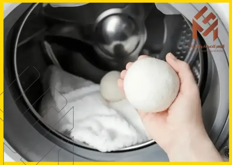 ما هي كرة التجفيف وكيف تعمل؟ 4 شخص يحمل كرة من القماش الأبيض في الغسالة - ما هي كرة التجفيف وكيف تعمل؟